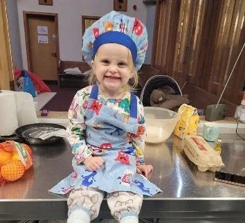 A young baker holding a bowl in the centre kitchen